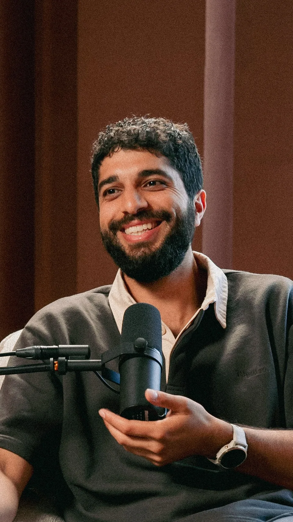 A guest mid-laugh at the mic, reframed vertically as a social clip